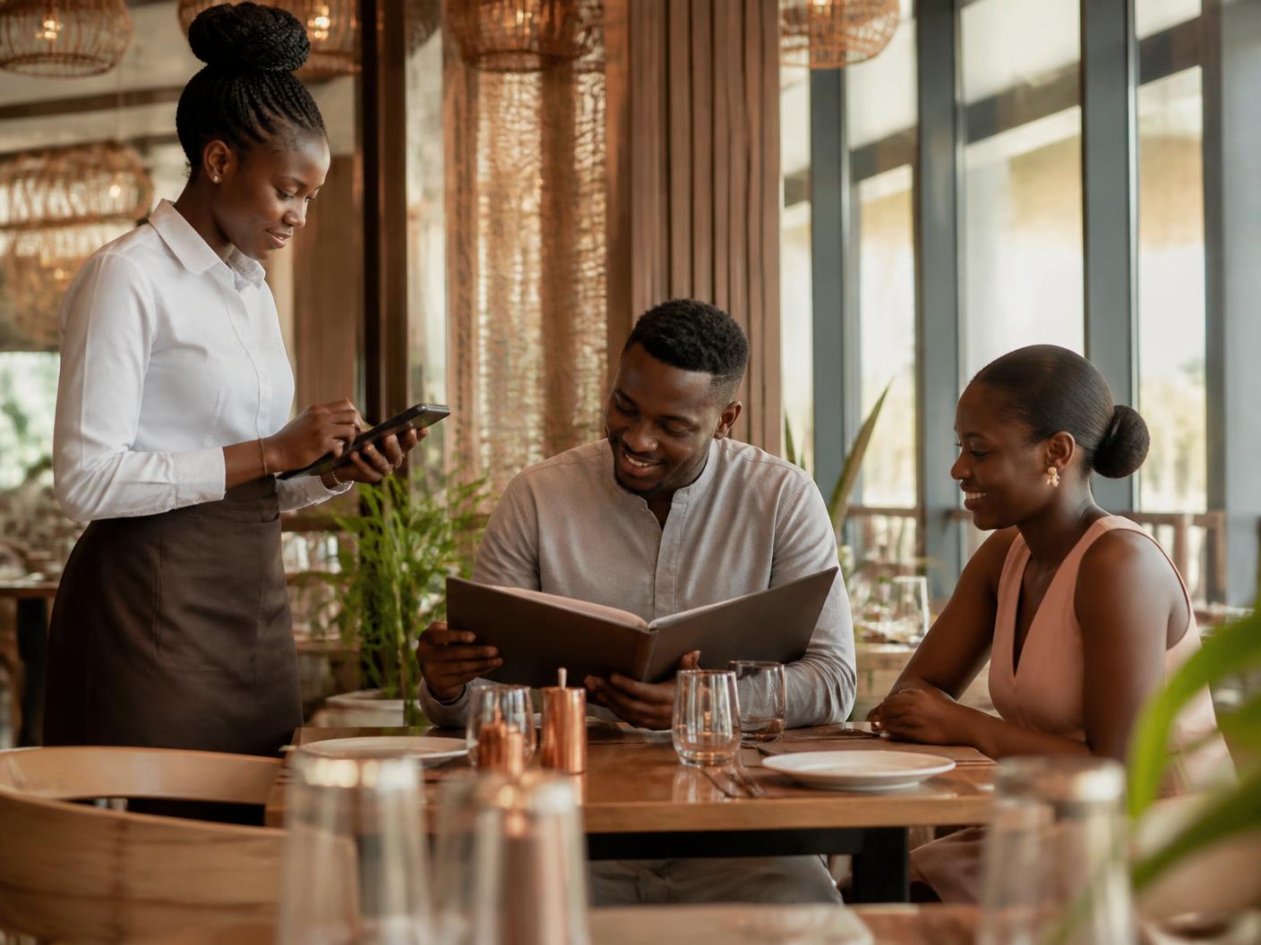 Serveuse en salle prenant une commande sur un terminal mobile